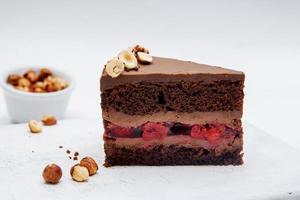 Piece of chocolate cake with cherries and hazelnut on white background photo