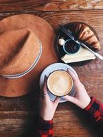 Woman hand's holding a cup of coffee on a wooden table background photo