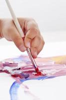 Asian boy use paintbrush and watercolor painting in paper photo