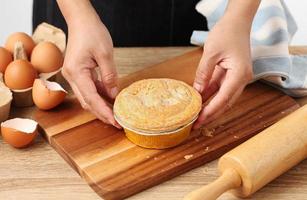 Woman hold meat pie on wooden tray photo