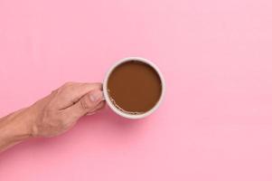 Hand holding a coffee mug on a pink background photo