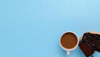 Taza de café, granos de café, café molido sobre un fondo azul. foto