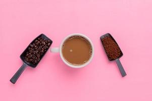 Taza de café y granos de café sobre un fondo rosa. foto