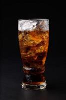 Cola in glass with clear ice cubes isolated on black background photo