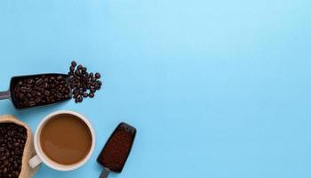 Coffee mug, coffee beans, ground coffee on a blue background photo