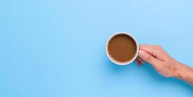 Hand holding a coffee mug on a blue background photo