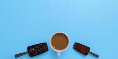 Taza de café, granos de café, café molido sobre un fondo azul. foto