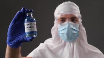 científico con traje protector muestra una vacuna desarrollada contra el covid. concepto de fin positivo de una pandemia global.