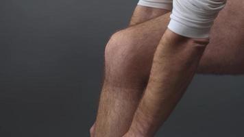 un hombre se pone un vendaje en la pierna cuando se torce foto