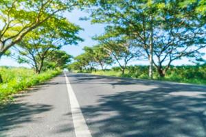 Abstract blur asphalt road in forest - boost up color processing style with sunflare effect photo