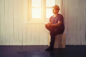 Young handsome man looking out his window at home in the room alone photo