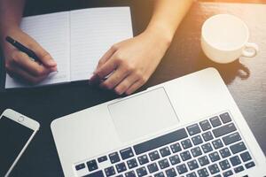 Close-up  of young beautiful woman hands writing and work with laptop photo