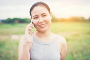 Young beautiful woman using smartphone and smiling in the park. photo