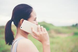 joven y bella mujer con smartphone y sonriendo en el parque. foto