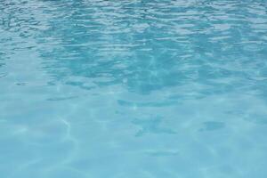 Swimming pool blue water with bright sun light reflections photo