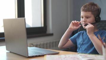 retrato de un niño enseñando lecciones en línea a distancia usando una computadora portátil e internet a través de un chat de video. aprendizaje a distancia en casa. foto