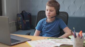 A smart little boy uses the computer to video chat with his teacher. E-education distance learning, home teaching, covid. Education learning online,Teenage student wear headphone photo