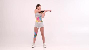 full length portrait female athletes with a kinesiotape on her body doing fitness exercises and stretching