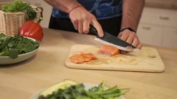 cocinar un plato de pescado fresco. el cocinero corta el salmón o la trucha frescos en una tabla de cortar en rodajas finas con un cuchillo de acero afilado. preparación de alimentos en la cocina de casa.