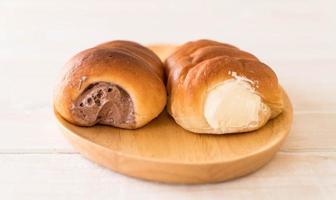 Bread roll with cream on wood plate photo