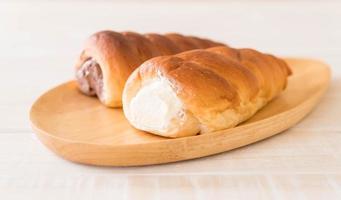 Bread roll with cream on wood plate photo