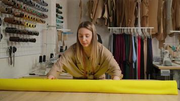 Close up of female designer unwinding a big yellow roll of fabric tissue on table at design studio photo