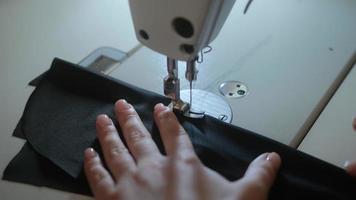 Stitching on sewing machine. Tailor sews on sewing machine. Close-up of woman's hand and sewing process. photo