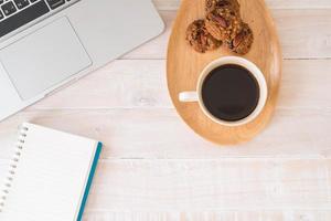 Black coffee and cookies with laptop and notebook on table photo