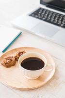 Black coffee and cookies with laptop and notebook on table photo