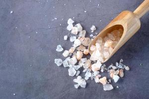 pink rock salt and wooden spoon on black background photo