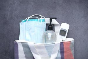 Surgical masks, thermometer and hand sanitizer on black background