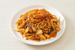 espaguetis secos con mariscos salteados tom yum - estilo de comida fusión foto