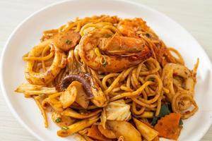 espaguetis secos con mariscos salteados tom yum - estilo de comida fusión foto