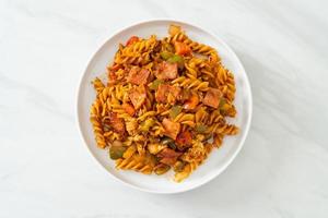 Stir-fried fusilli pasta with ham and tomato sauce photo