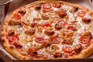 Sabrosa pizza en rodajas con mariscos y tomate sobre un fondo de hormigón foto