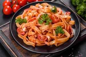 Fettuccine pasta with shrimp, cherry tomatoes, sauce, spices and herbs photo