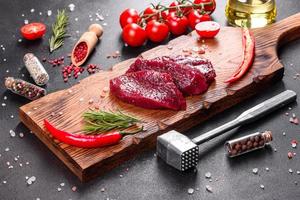 Fresh Raw Beef steak Mignon, with salt, peppercorns, thyme, tomatoes photo