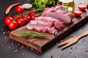 Fresh pieces pork ready to cook on a dark background in the kitchen photo