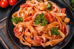 Fettuccine pasta with shrimp, cherry tomatoes, sauce, spices and herbs photo