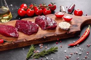 Fresh Raw Beef steak Mignon, with salt, peppercorns, thyme, tomatoes photo