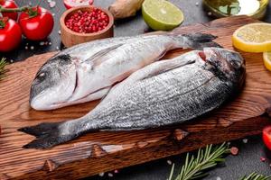 Pescado dorado crudo con especias cocinando sobre tabla de cortar foto