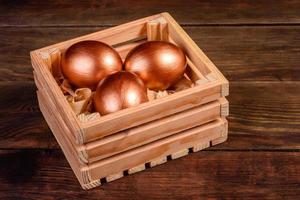 Easter eggs in gift wooden box on dark wooden background photo