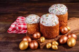 Huevos de pascua de oro y bronce y pastel de pascua sobre un fondo oscuro foto