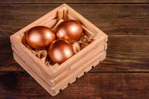 Easter eggs in gift wooden box on dark wooden background photo