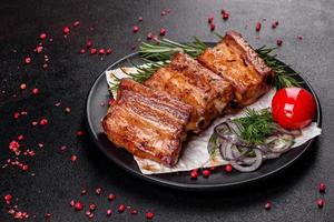Fried ribs with rosemary, onion, sauce on a concrete background photo
