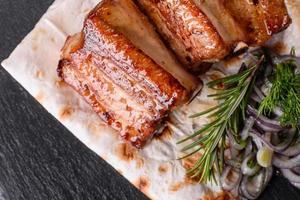 Fried ribs with rosemary, onion, sauce on a concrete background photo