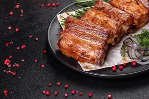 Fried ribs with rosemary, onion, sauce on a concrete background photo