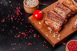 Costillas fritas con romero, cebolla, salsa sobre un fondo de hormigón foto