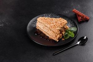 Fresh delicious cake napoleon with cream on a dark background photo