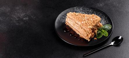 Fresh delicious cake napoleon with cream on a dark background photo